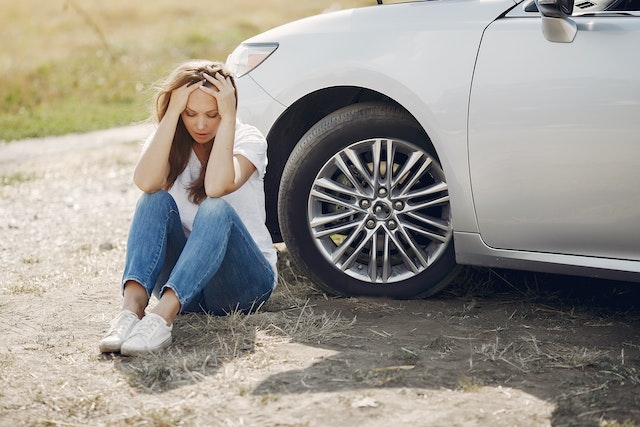 girl sitting by damaged car