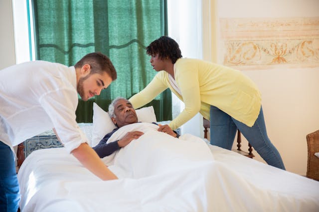 old man getting into bed with help