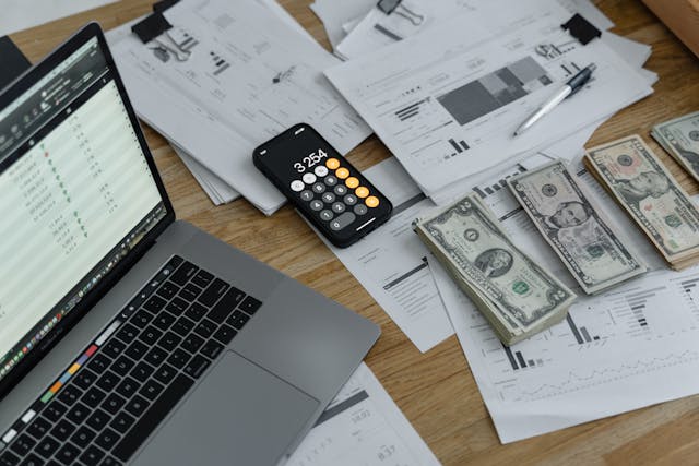 person using calculator near stacks of money