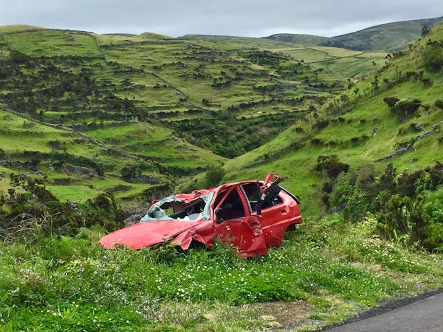 damaged red car on side of the road