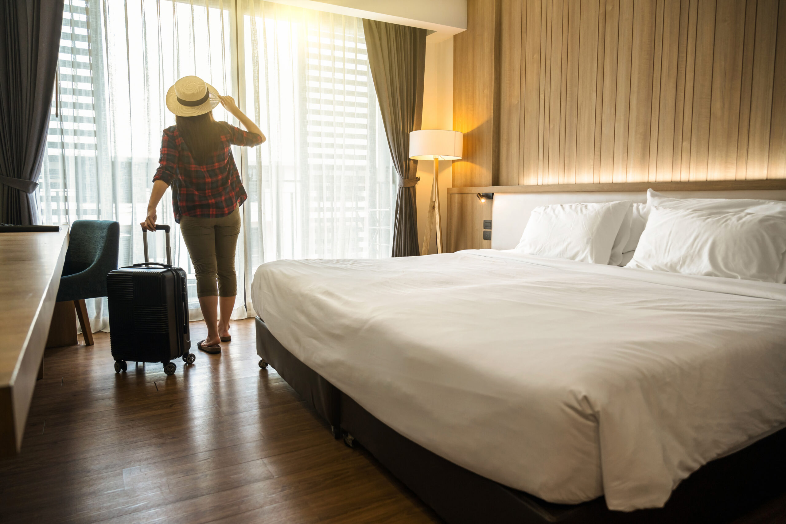 traveler woman standing with baggage in bedroom vacation rental