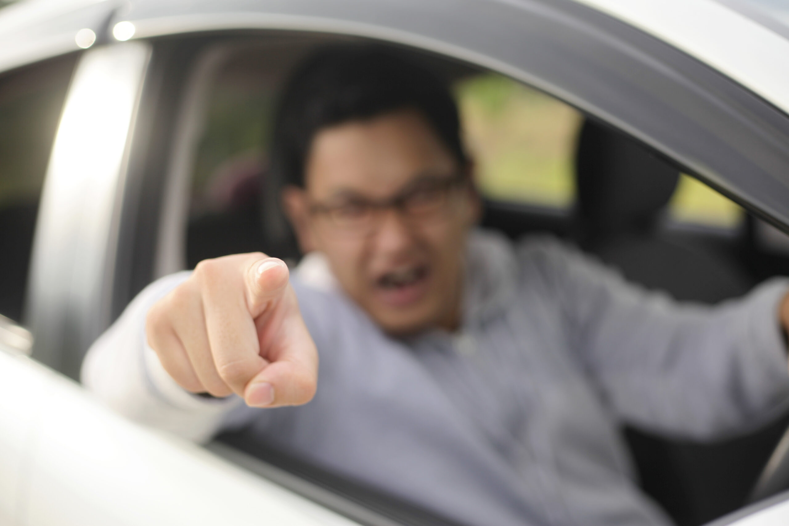 Portrait of male driver getting mad and angry from the traffic, screaming and pointing from his car